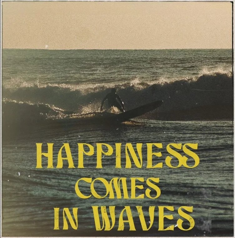 A person surfing on a wave in the ocean during sunset with the text 'Happiness Comes in Waves' overlaid.