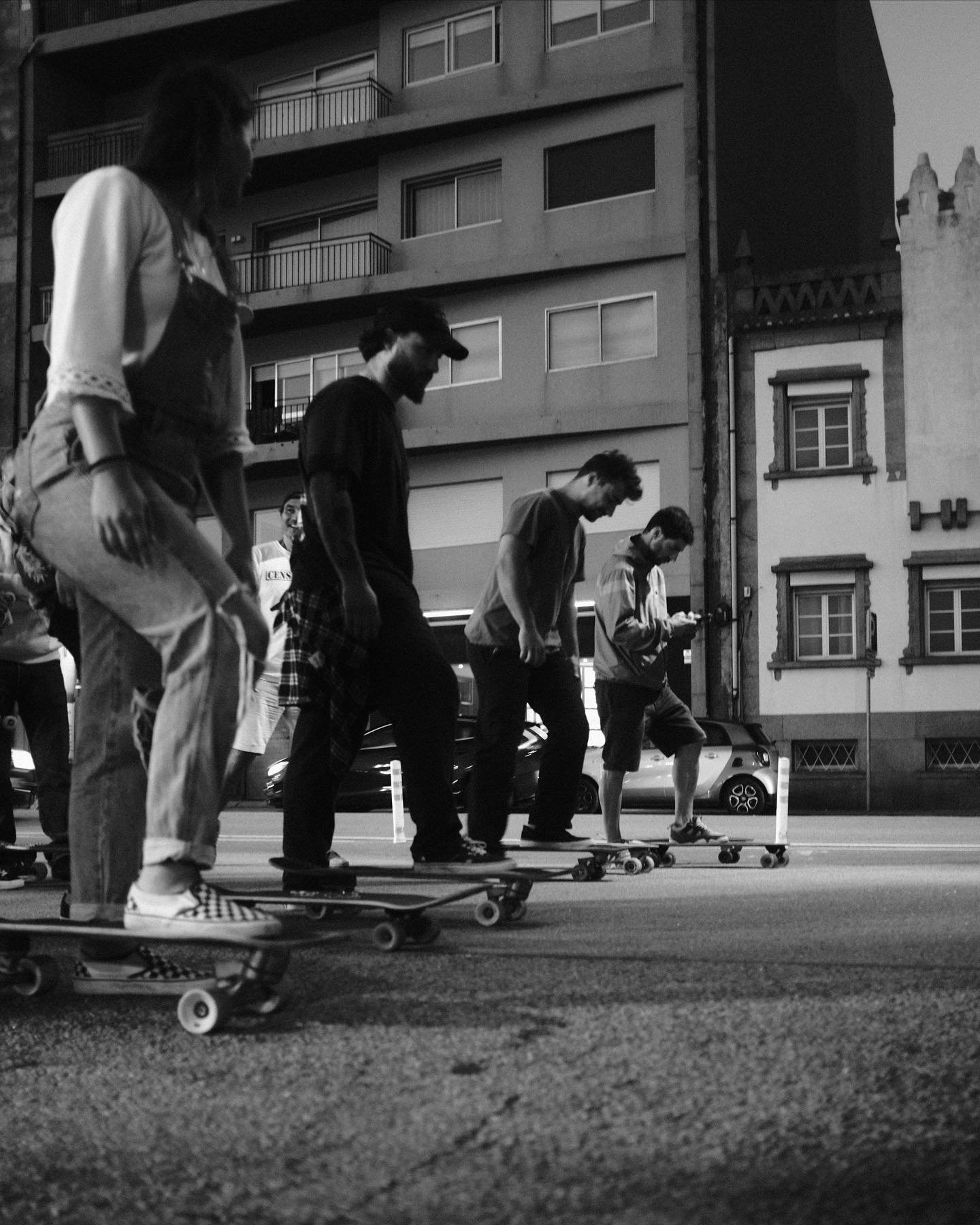 Group of young people skateboarding on an urban street at dusk, black and white photo.