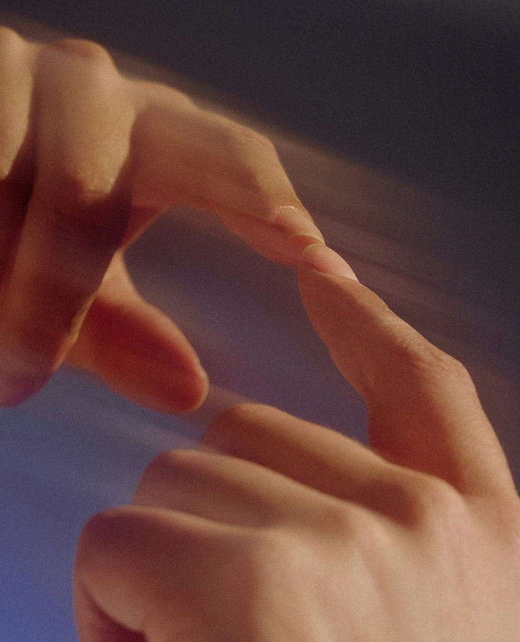 Close-up of two fingers touching, with a plain dark background.