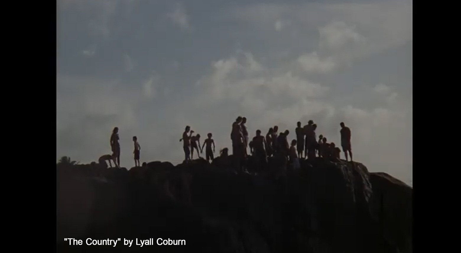 Silhouettes of a group of people standing and sitting on a rocky hilltop against a cloudy sky, with text indicating the image is "The Country" by Lyall Coburn.